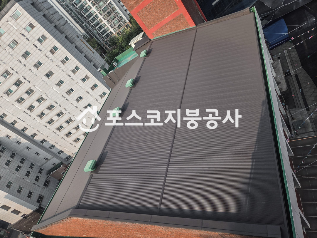 넓은 교회 지붕을 회색 칼라강판으로 새로 덮은 모습